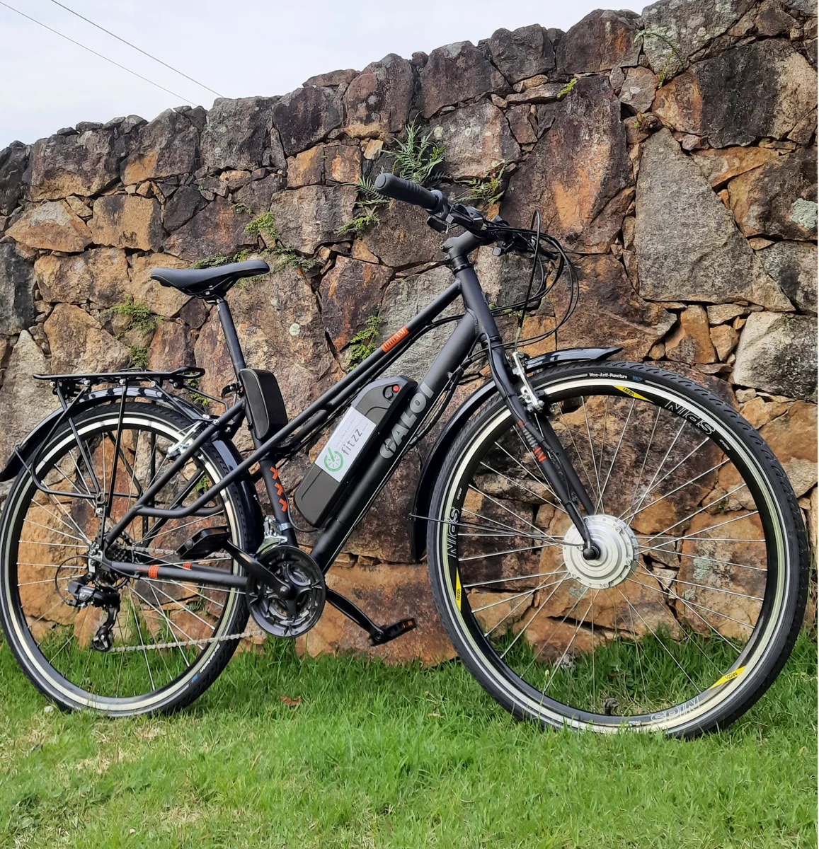 Bicicleta equipada com kit URBAN-350, fotografada junto a um muro de pedras.